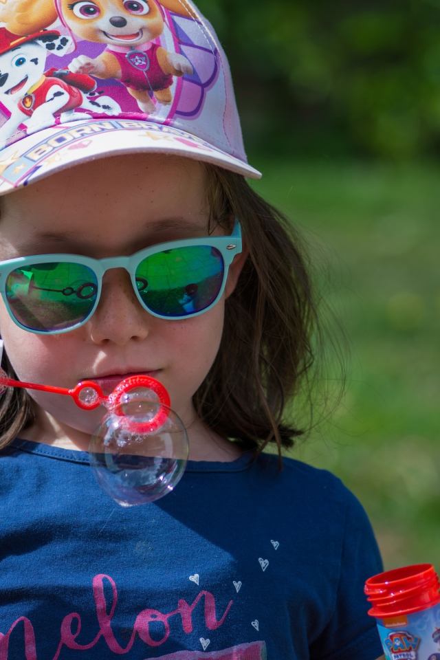 Маленькая девочка в очках с мыльными пузырями