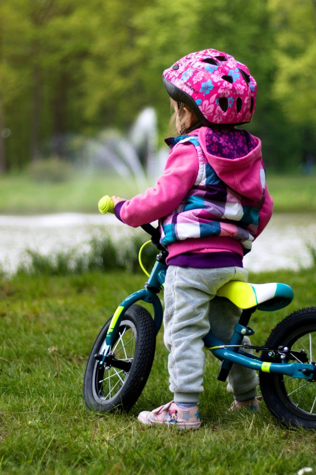 Маленькая девочка на велосипеде в парке 