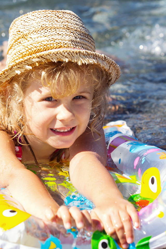 Маленькая девочка на надувном матрасе в воде