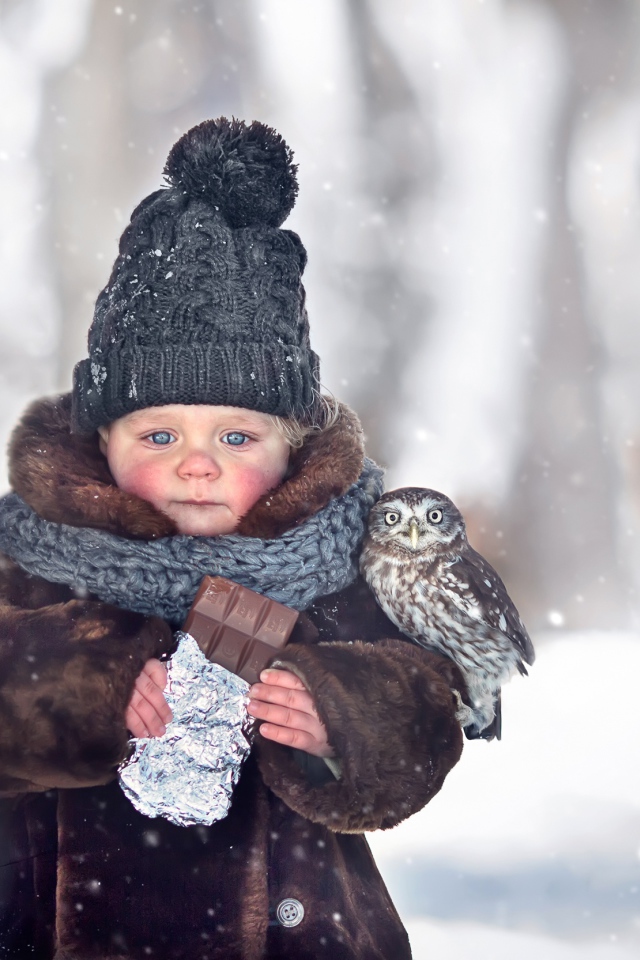 Маленькая девочка с шоколадкой в руках на улице зимой