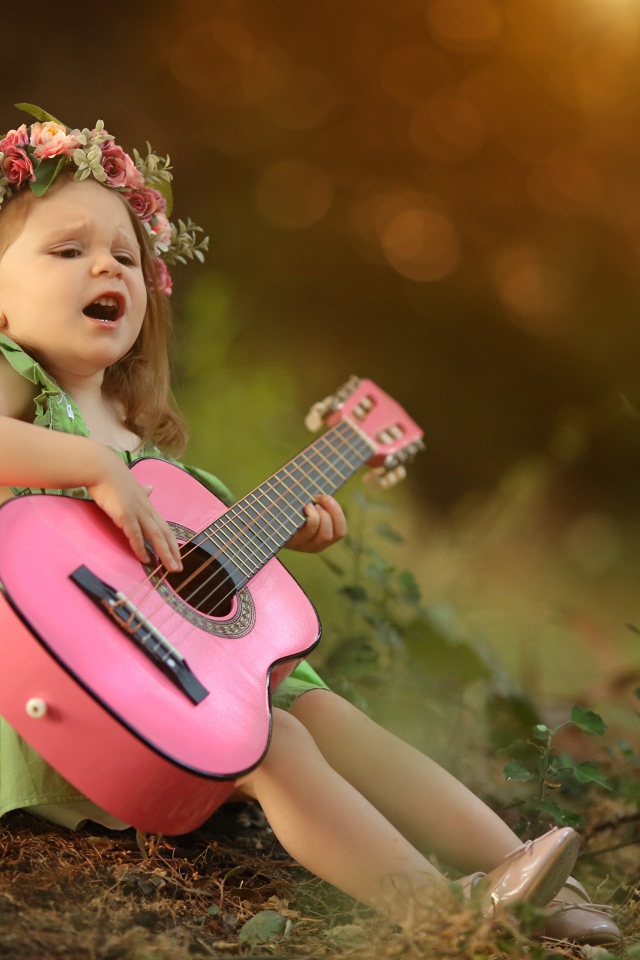 Маленькая девочка с гитарой под деревом 
