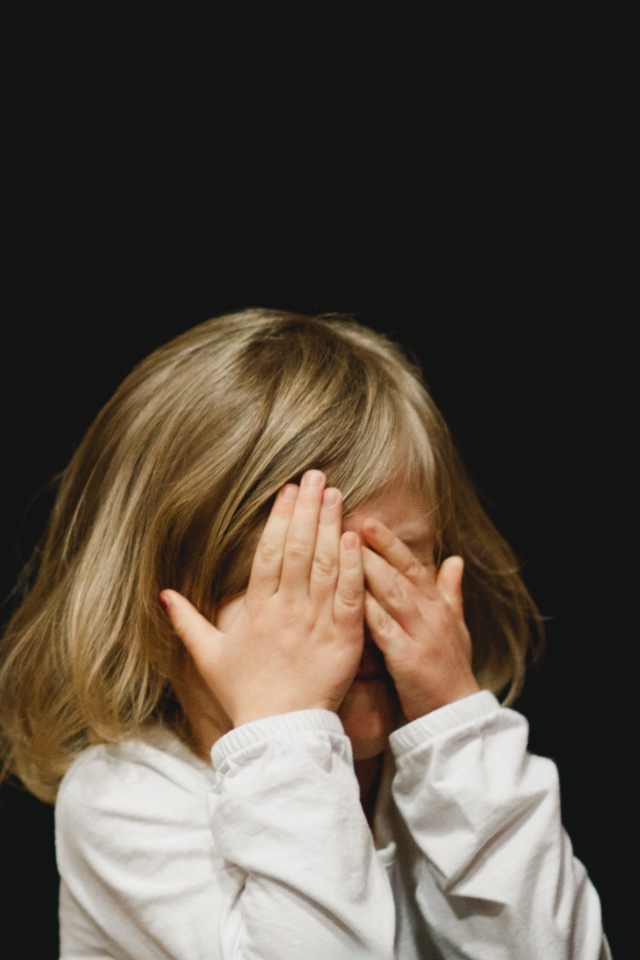 Маленькая девочка с закрытыми глазами на черном фоне 