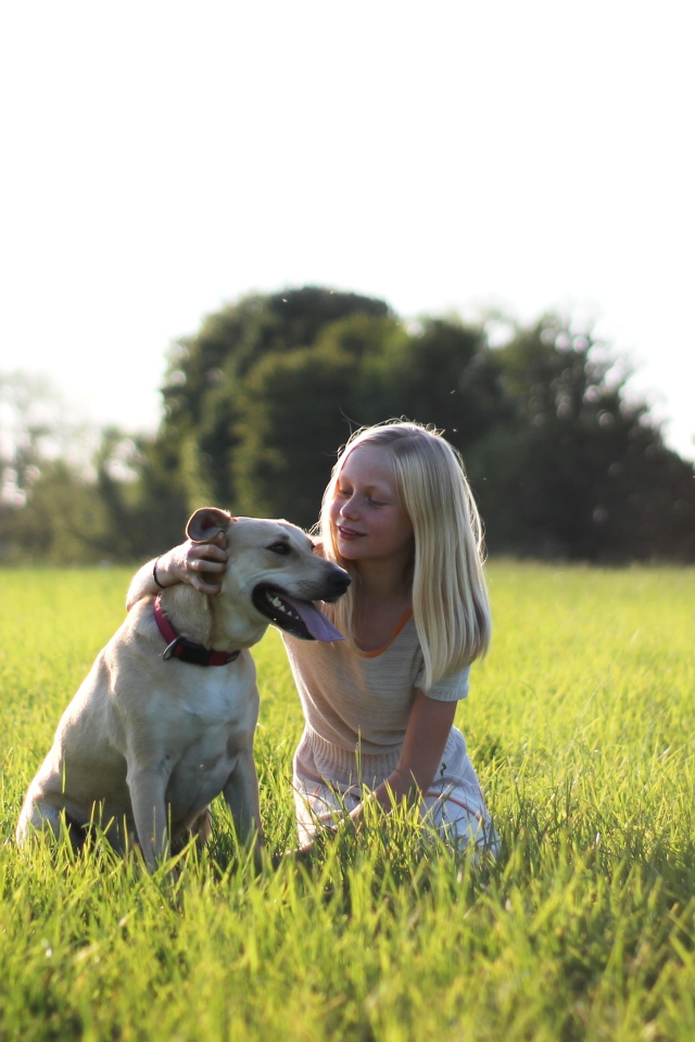Маленькая девочка с собакой в зеленой траве