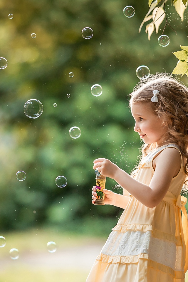 Маленькая девочка с мыльными пузырями в саду 