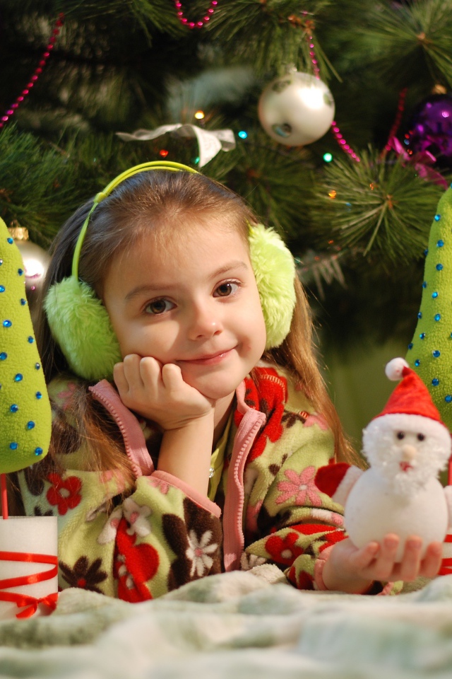 Маленькая девочка с игрушками под елкой 