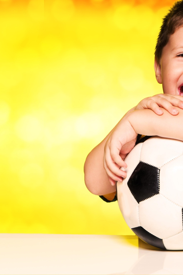 Маленький довольный мальчик с футбольным мячом