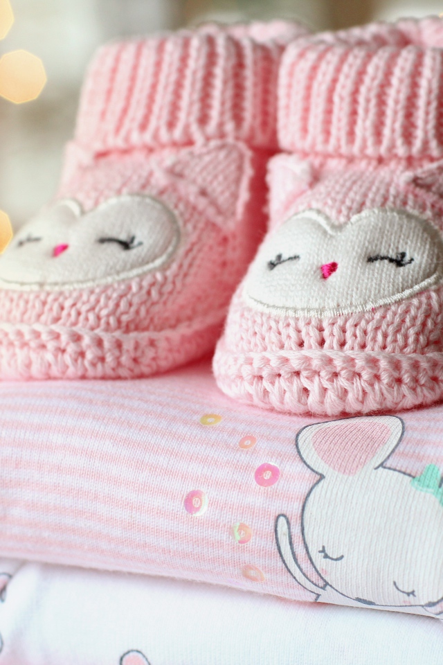 Маленькие розовые пинетки и одежда для малыша 