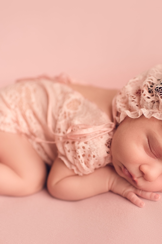 Маленький спящий грудной ребенок в розовом костюме