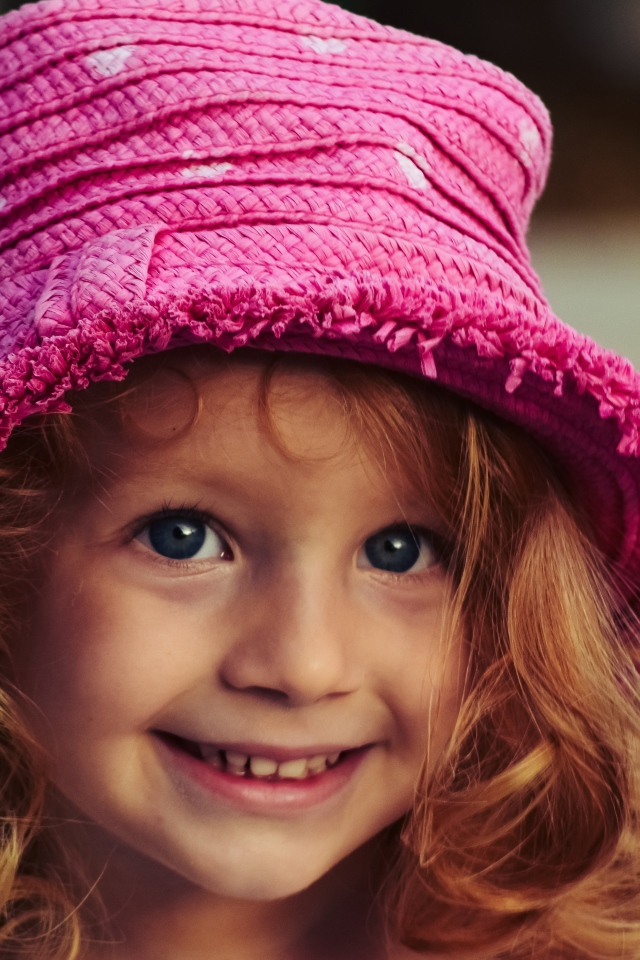 Маленькая улыбающаяся девочка в розовой шляпе