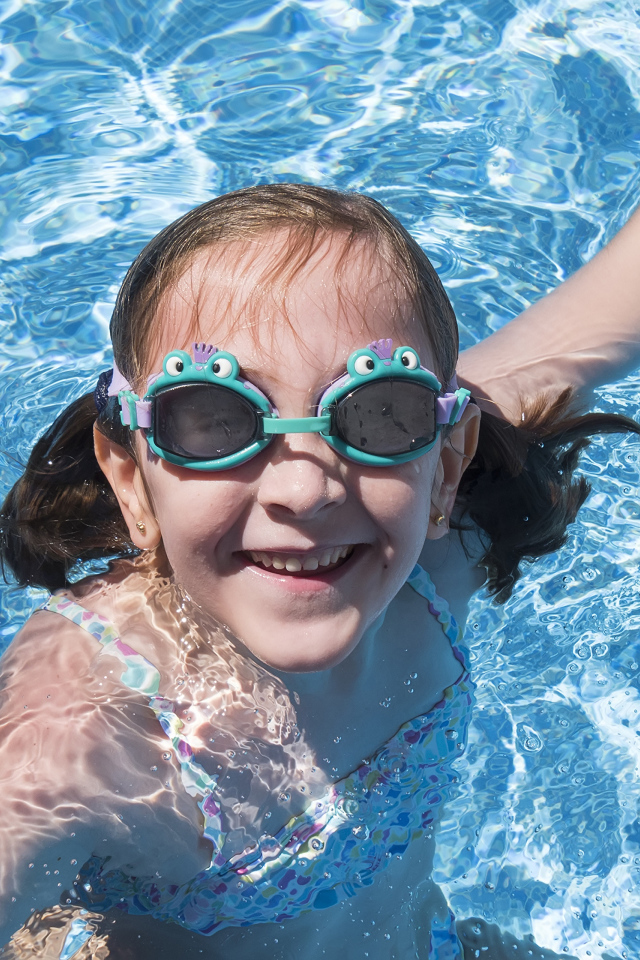 Маленькая улыбающаяся девочка в очках в бассейне 