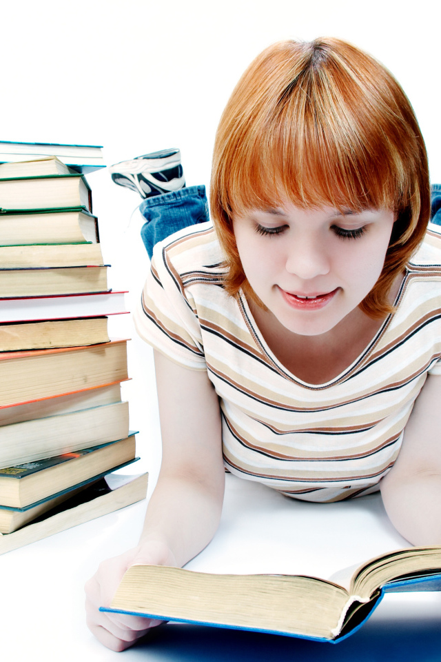 Рыжеволосая девочка школьница читает книги на белом фоне 