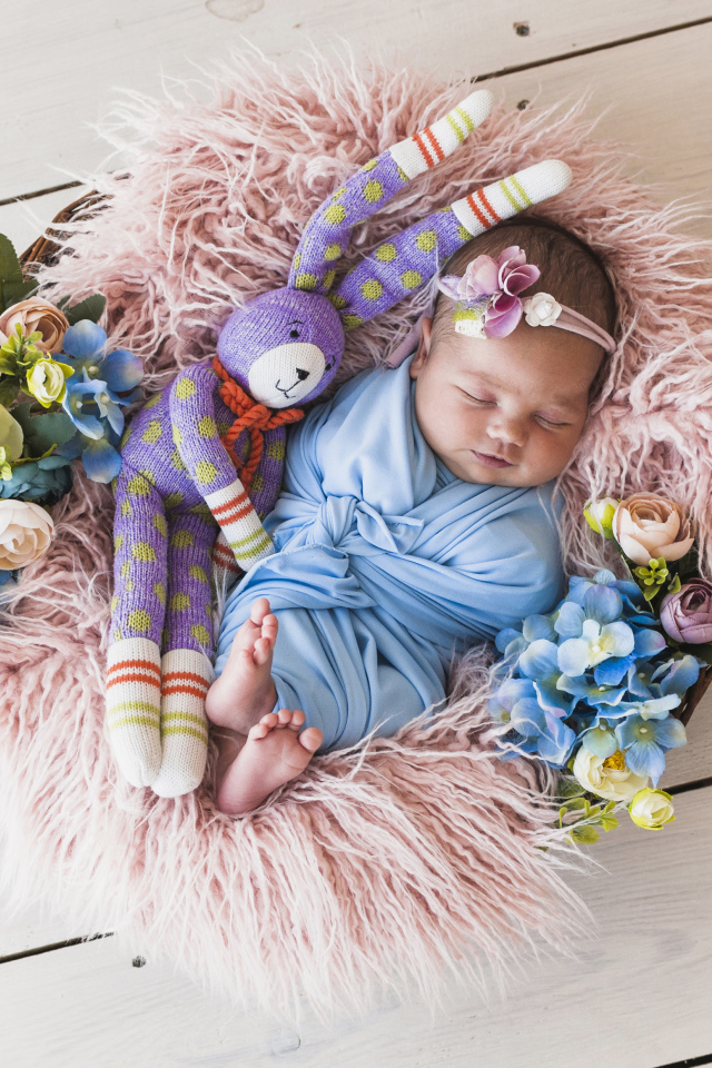 Спящий грудной ребенок с игрушкой в корзине 