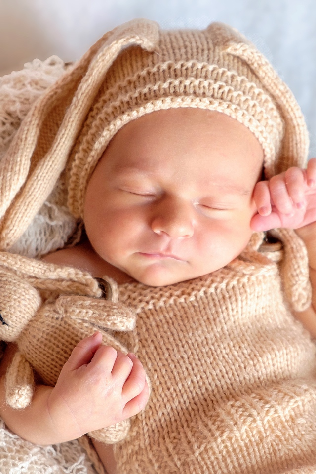 Спящий грудной ребенок в вязаном костюме