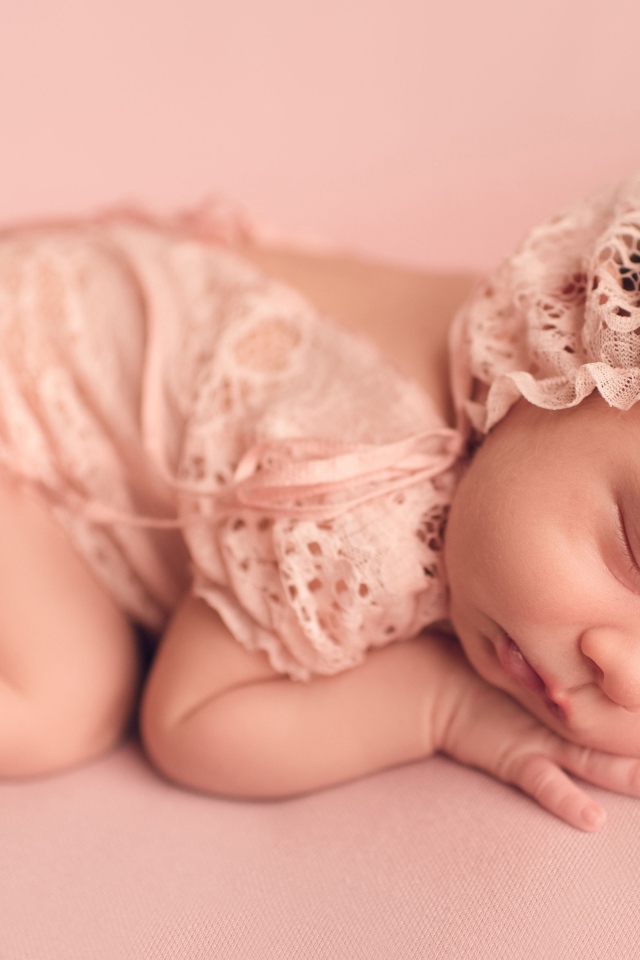 Спящий грудной ребенок в розовом костюме 