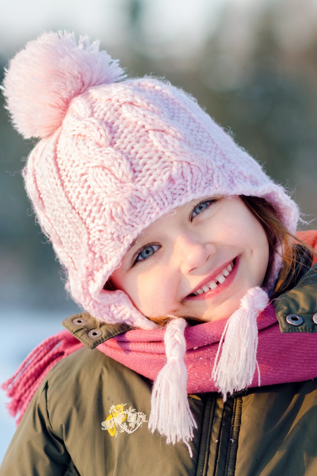 Улыбающаяся голубоглазая девочка в розовой шапке 