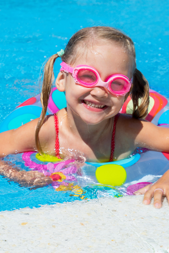 Улыбающаяся девочка с кругом в бассейне 