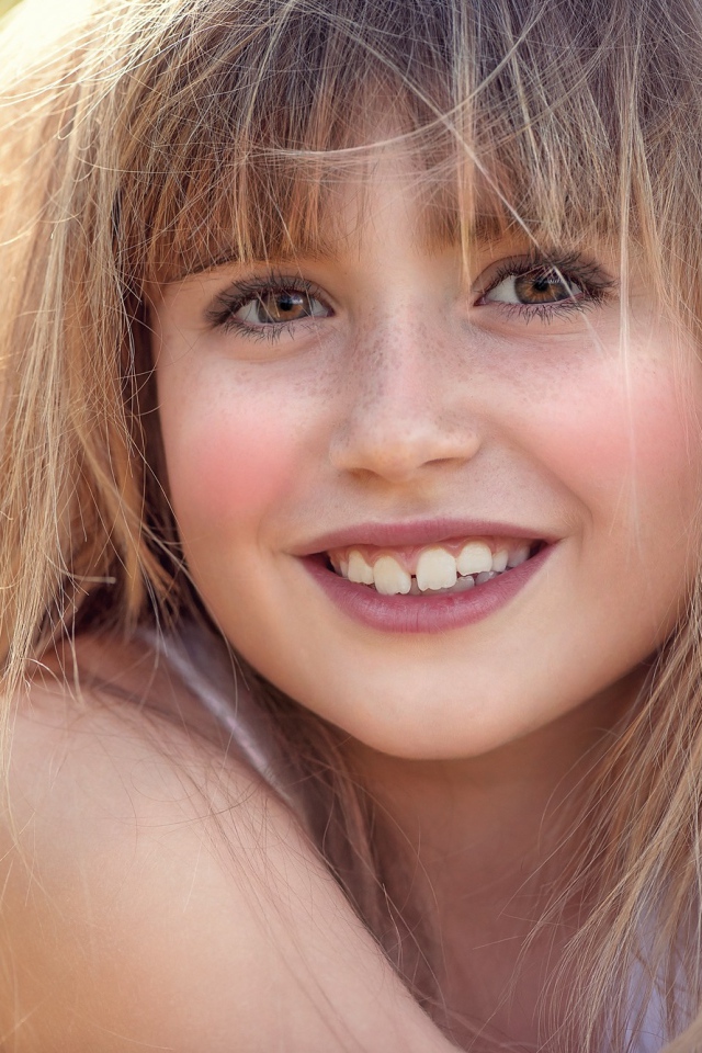 Улыбающаяся девочка с веснушками на лице 