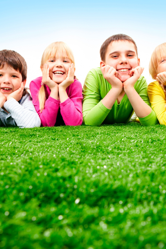 Улыбающиеся дети лежат на зеленой траве
