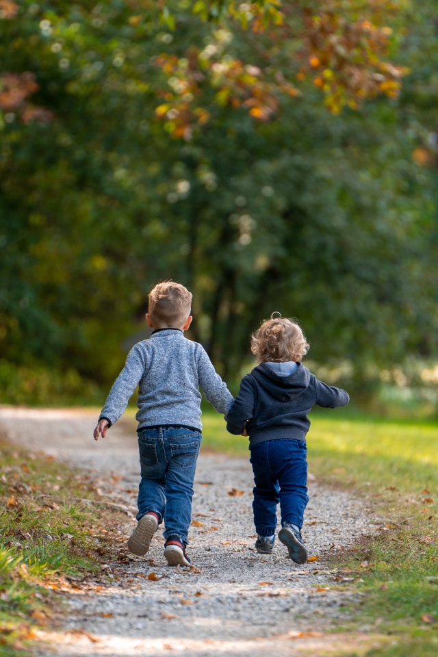 Два маленьких ребенка гуляют в осеннем парке
