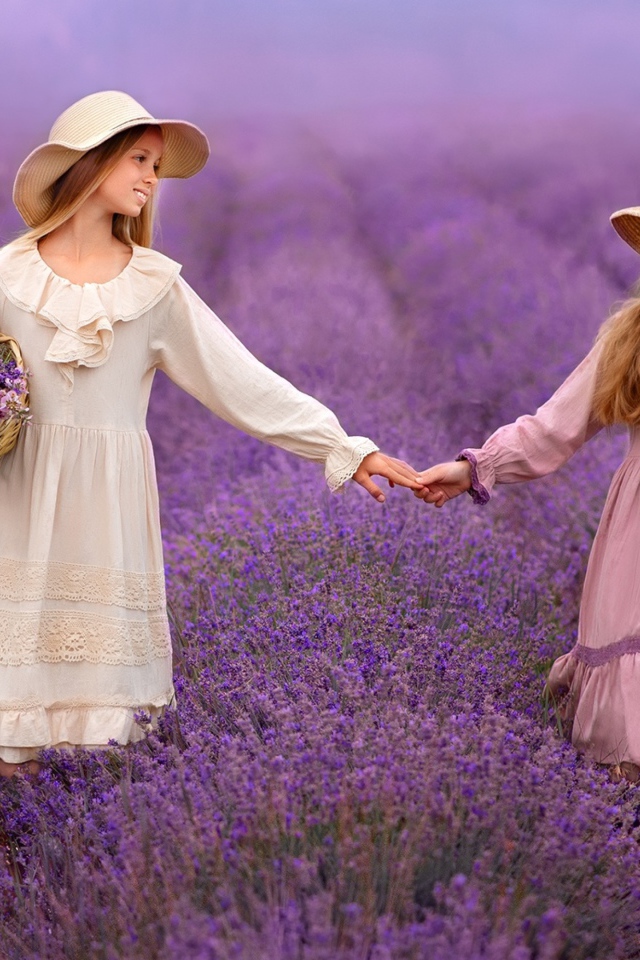 Две маленькие девочки идут по лавандовому полю 