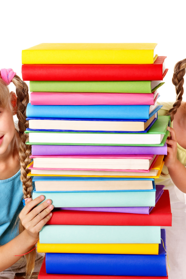 Две маленькие девочки с разноцветными книгами на белом фоне