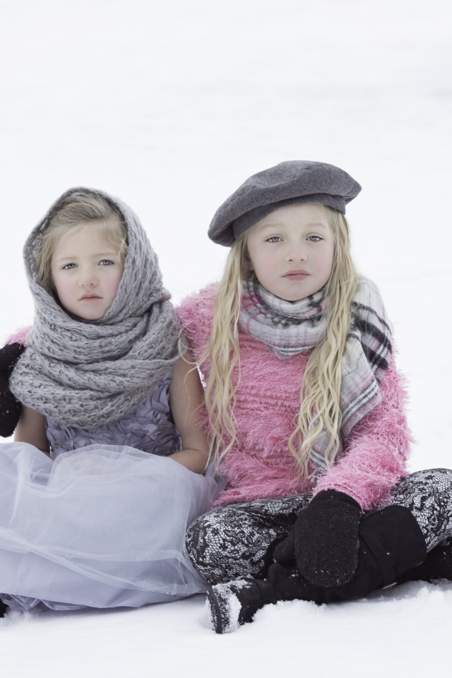 Две маленьких сестры сидят на снегу 