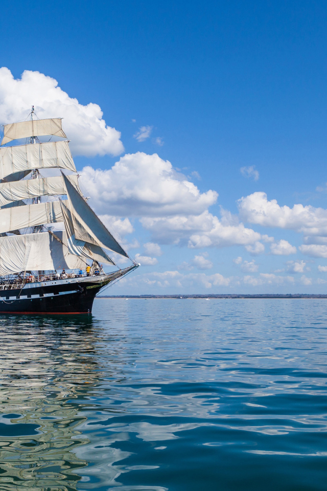 Большой парусный барк в небе над морем с белыми облаками 