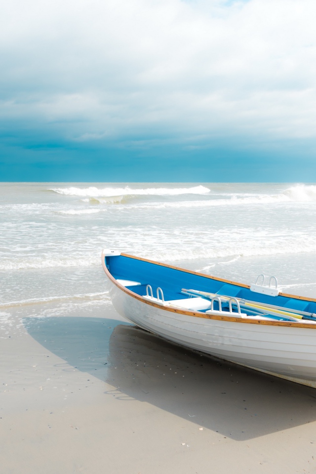 Лодка стоит на белом песке у моря 