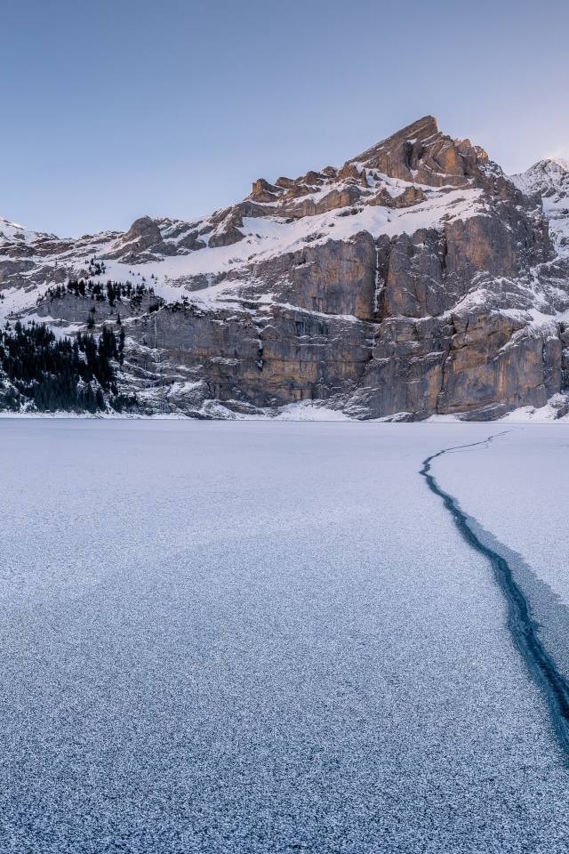 Трещина в озере на фоне заснеженных гор зимой