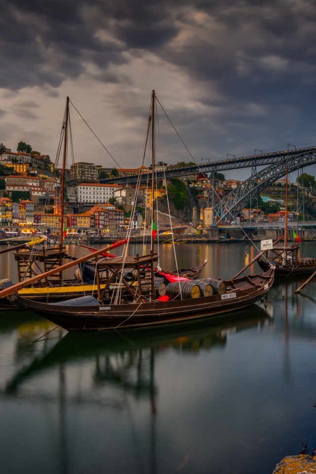 Лодки в порту на фоне моста и города на закате 