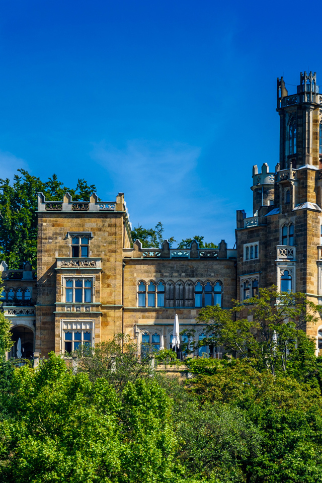 Старинный замок в зарослях деревьев на фоне голубого неба, Германия