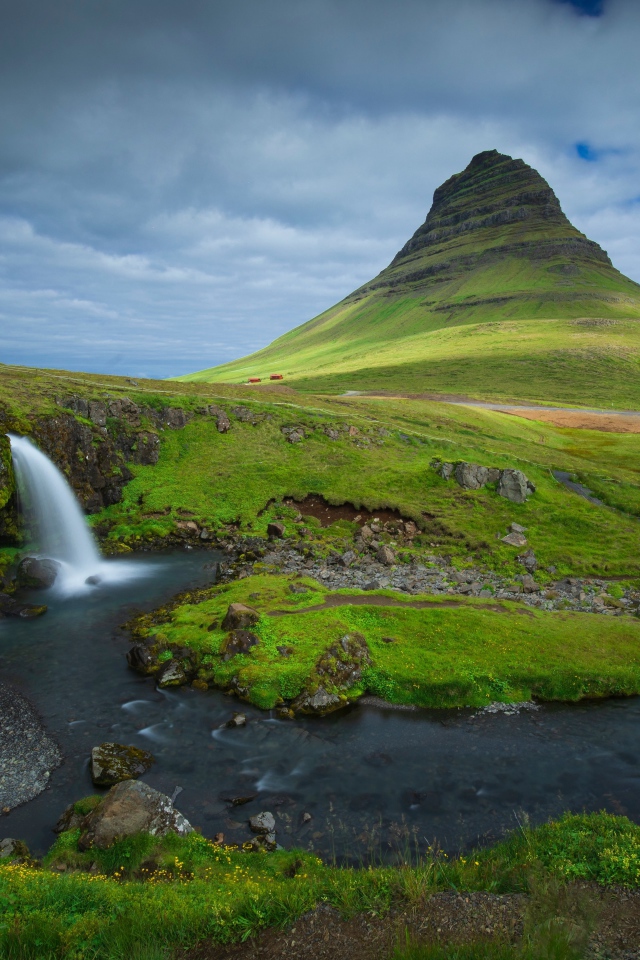 Вид на маленький водопад и покрытую зеленью гору, Исландия