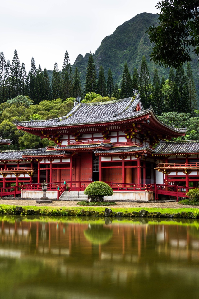 Red temple building near the water on a background of a mountain, Japan