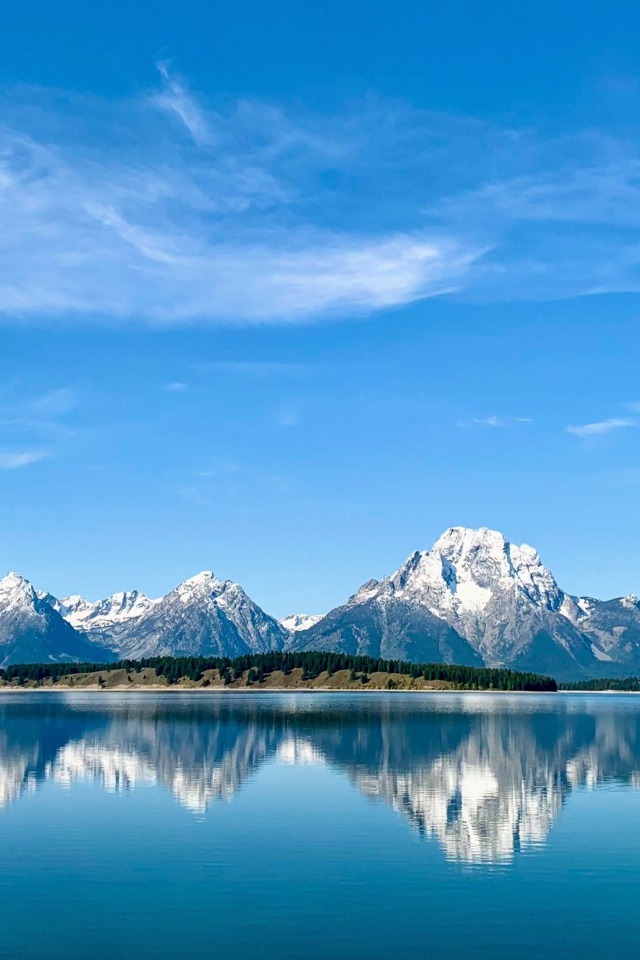 Вид на заснеженные горы под голубым небом у озера, Национальный парк Гранд Титон, Вайоминг. США