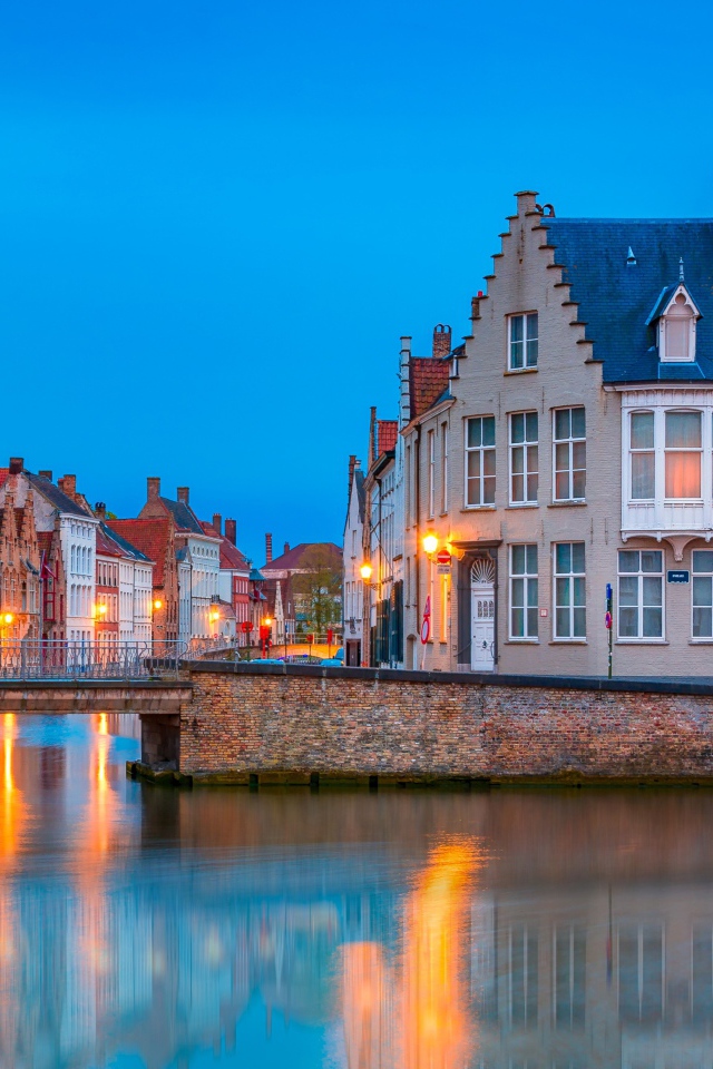 Большие дома и фонари отражаются в воде канала вечером