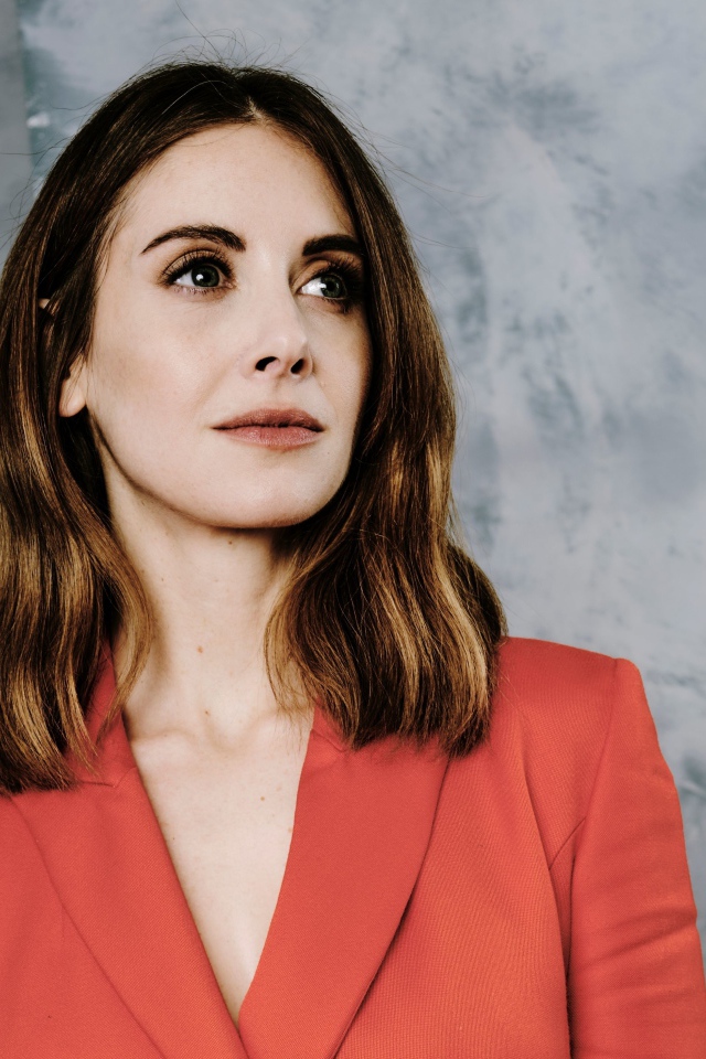 Актриса Элисон Бри в красном пиджаке на сером фоне