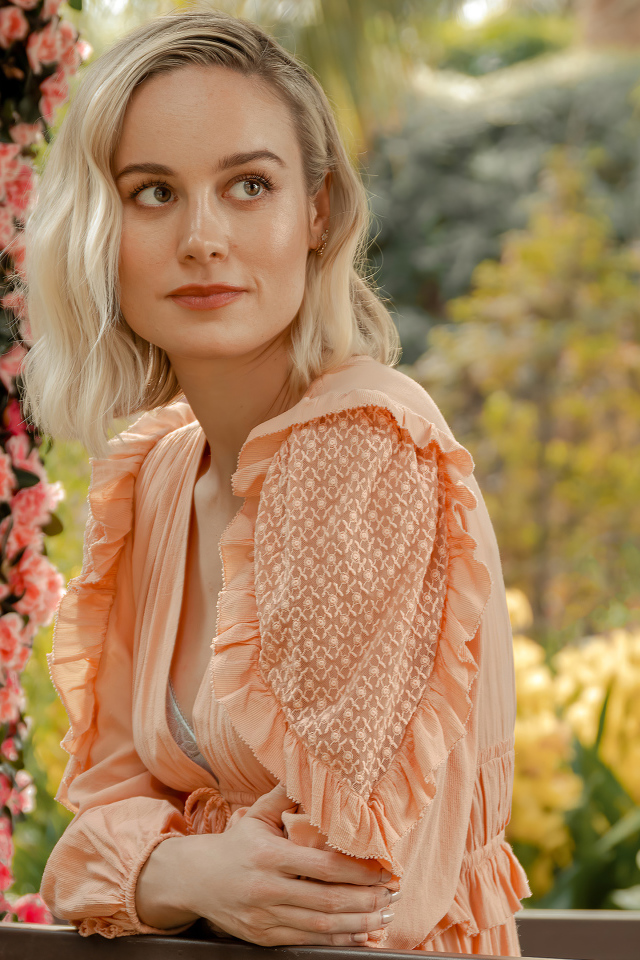 Актриса Бри Ларсон сидит у кустов с розовыми цветами