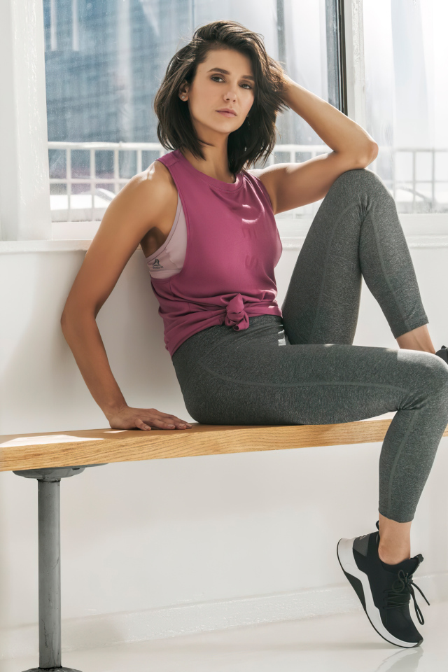 Актриса Нина Добрев сидит на лавке в спортивном костюме