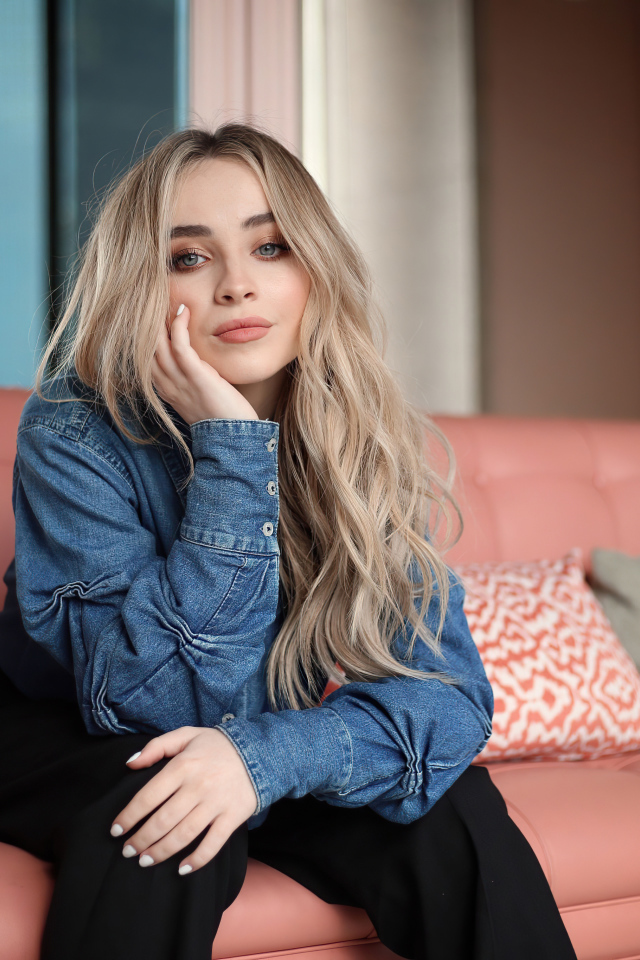 Актриса Сабрина Карпентер сидит на диване в комнате