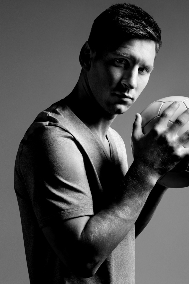 Аргентинский футболист Лионель Месси с мячом в руках на сером фоне