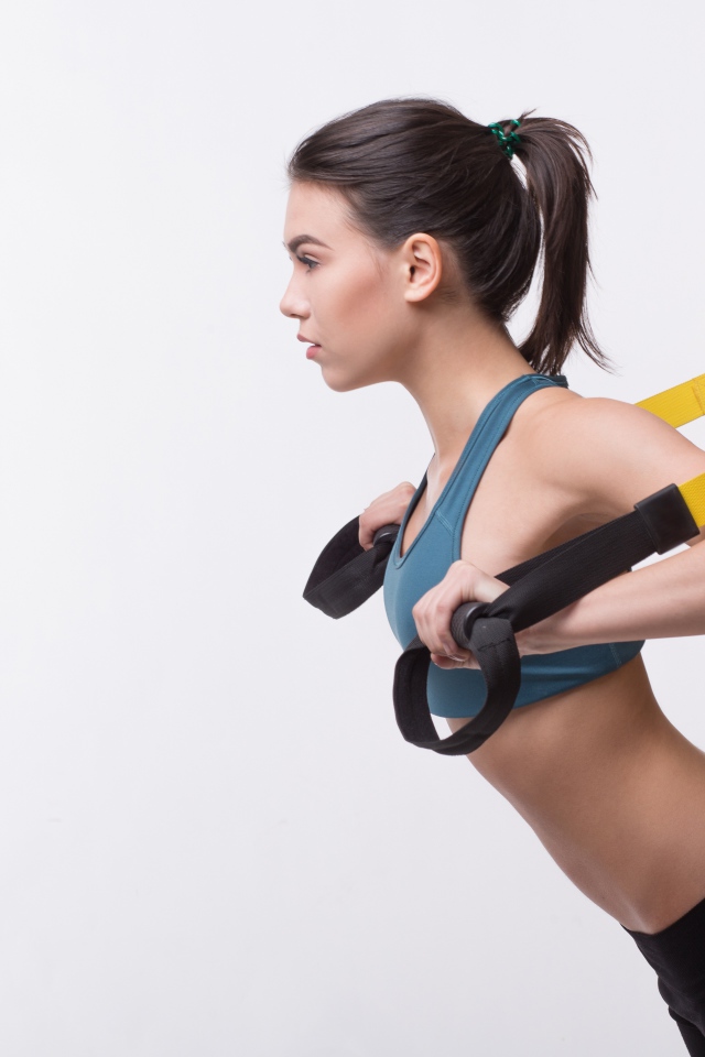 Спортивная девушка занимается в спортзале на белом фоне 