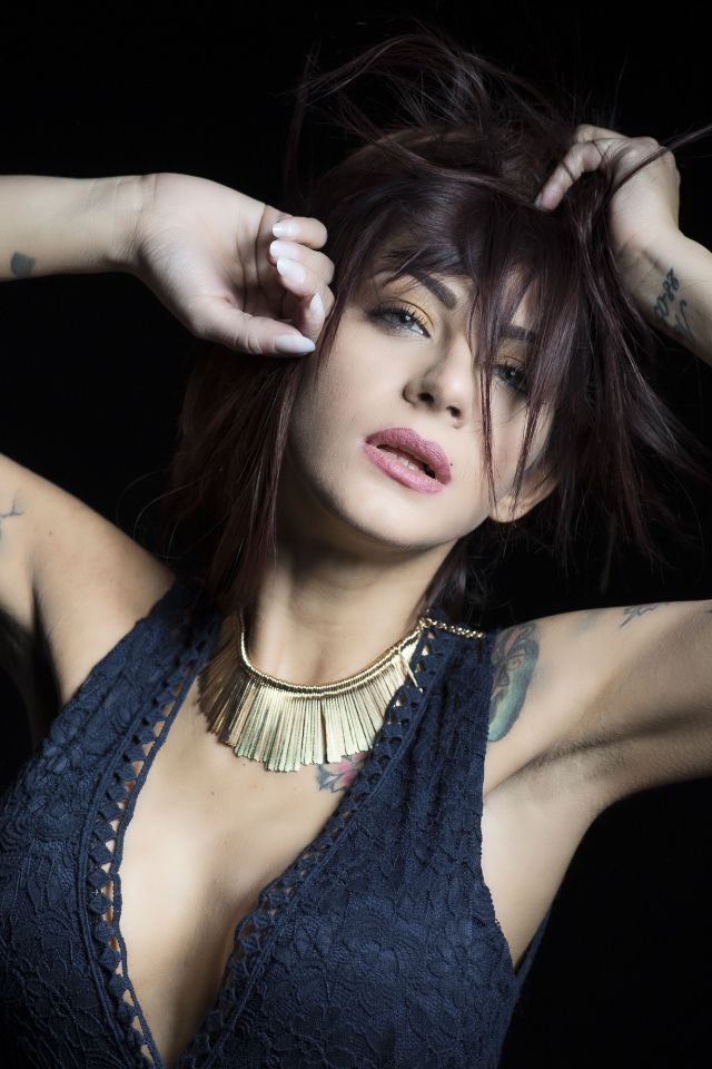Красивая девушка в черном платье с татуировками на теле 