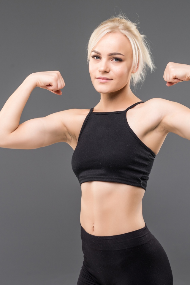Красивая стройная спортивная девушка показывает мускулы