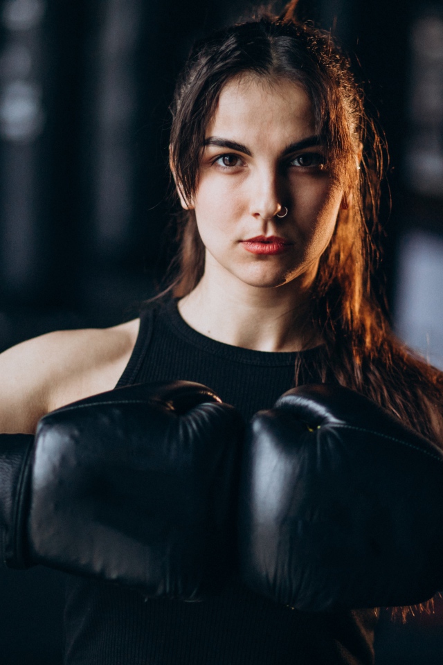 Девушка боксер с черными перчатками на руках 