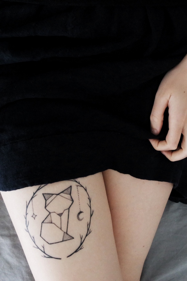 Татуировка лиса на ноге у девушки в черном платье