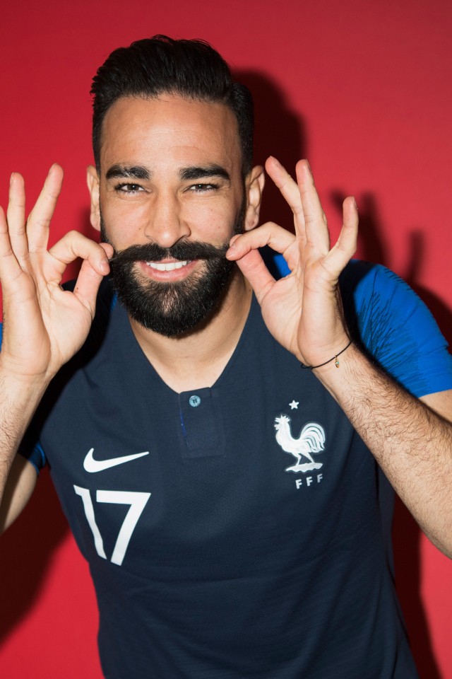 Французский футболист Адиль Рами на красном фоне