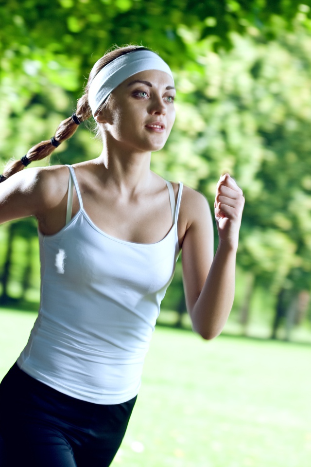 Девушка спортсменка в белой майке занимается бегом