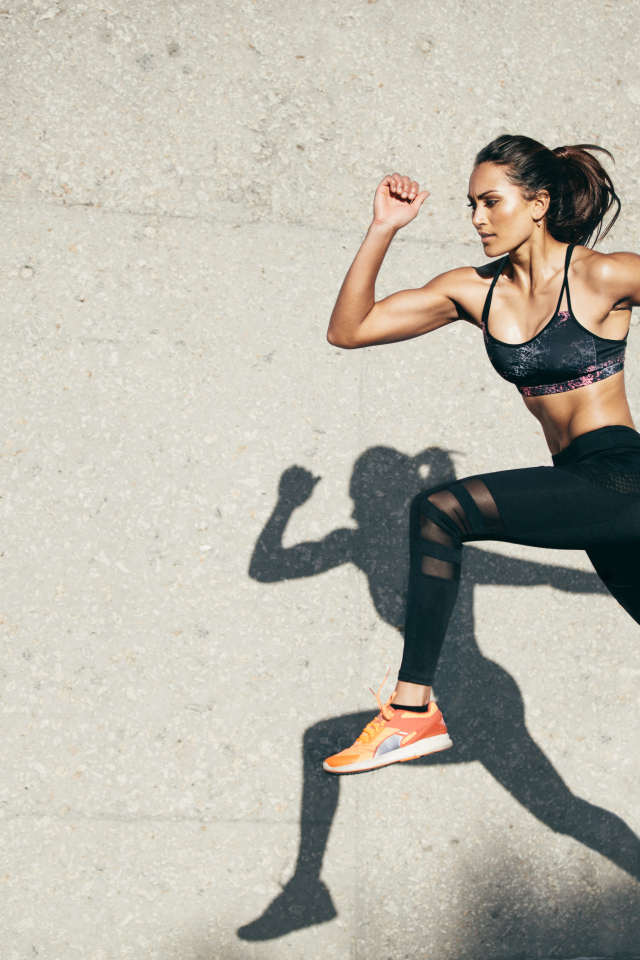 Девушка спортсменка бежит на стадионе 