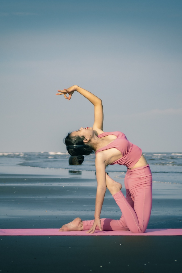 Девушка занимается йогой у моря 