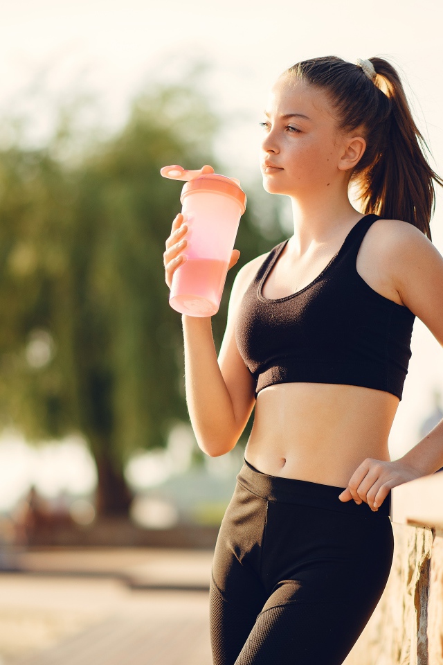 Девушка в черном спортивной форме с водой 